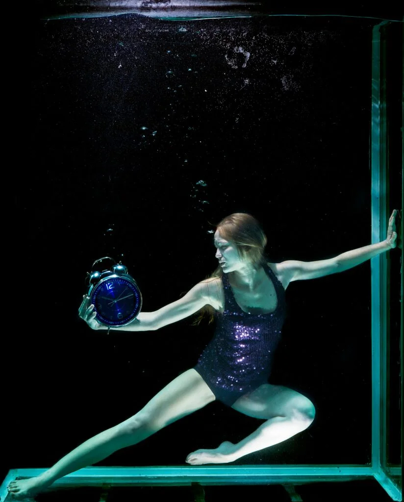 A woman in a pool with a clock to show personal time
