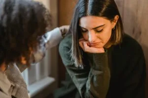 two women , one of them is showing distress and the other support her