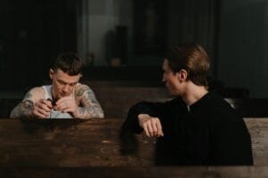 A priest with a man with multiple tattoes